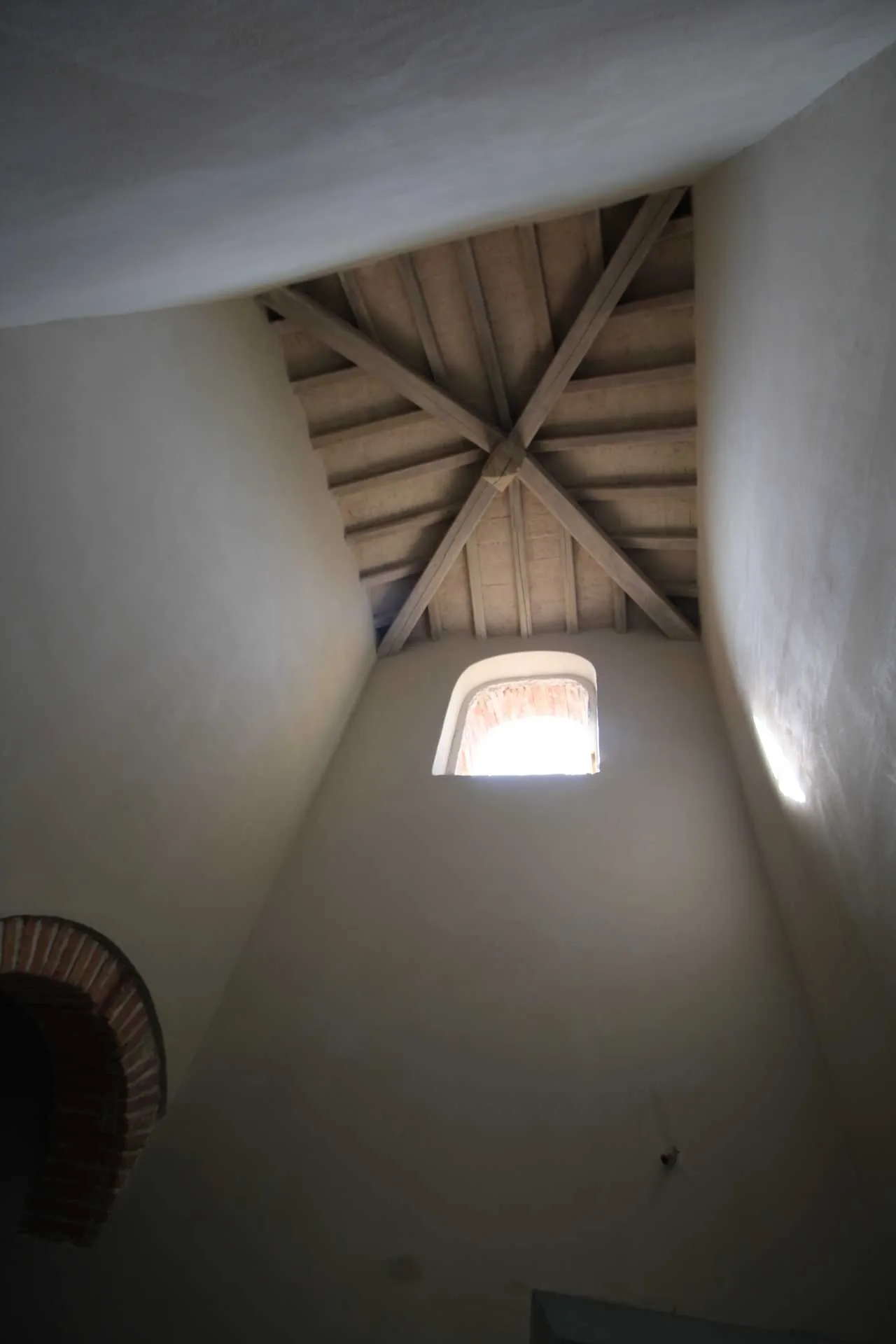 Soffitto con travi in legno a padiglione e piccola finestra